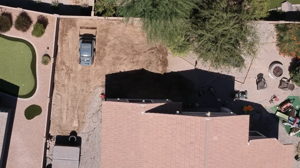 Drone view looking down at bobcat leveling out the yard