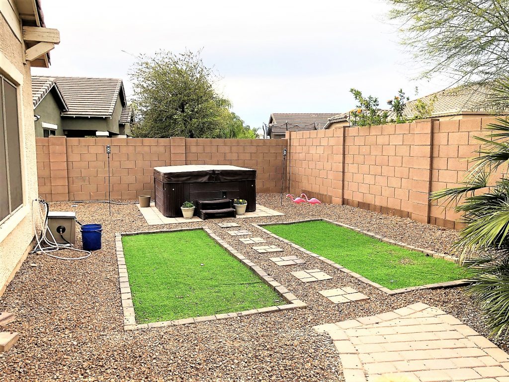 Finished yard with artificial turf and hot tub.